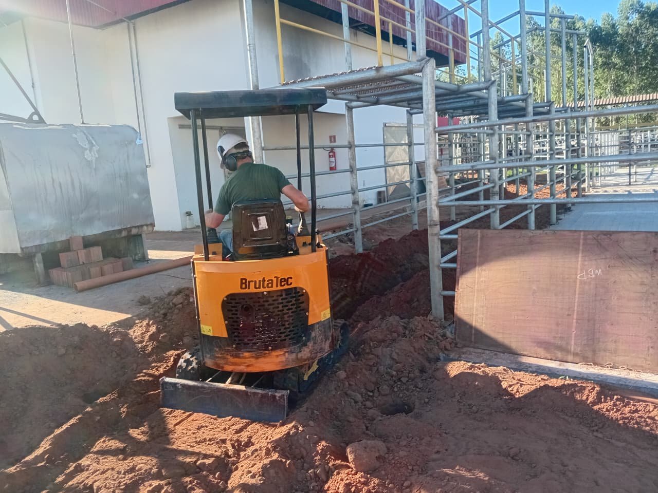 Operador com EPI conduzindo a mini escavadeira